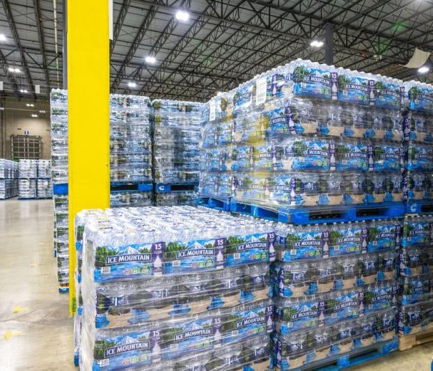 Ice Mountain Natural Spring Water pallet on warehouse floor, showcasing clear bottles with blue mountain label and shrink-wrapped cases.